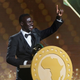 Sadio Mané on stage dressed in a black bow tie suit with his African Footballer of the Year award